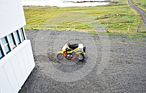 Yellow sidecar motorcycle parked next to the white hostel building road trip in Iceland, travel, vehicle