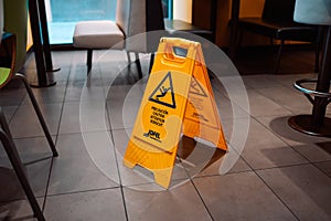 Yellow Caution slippery wet floor sign on the wet ground