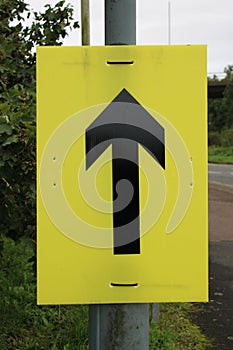 Yellow sign with Black arrow used for marathon runners