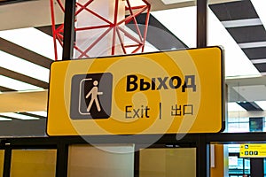 Yellow sign with a black inscription exit in different languages at the airport