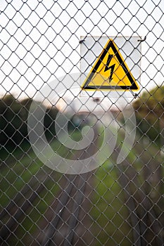 The yellow sign of high voltage over the railroad