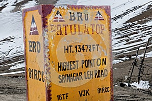 Yellow sign marking the summit of a high mountain pass in the Himalayas