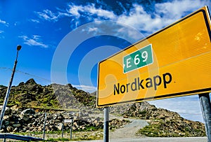 Yellow sign surrounded by mountains under a blue sky