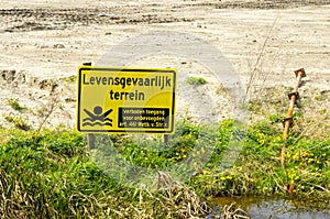 Yellow sign with text perilous area forbidden unauthorized access photo