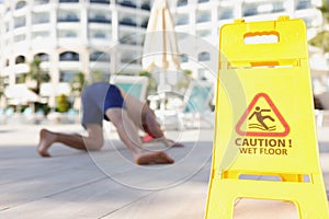 Yellow sign with warning caution wet floor standing near falling man closeup