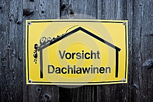 Yellow sign with warning of roof avalanches