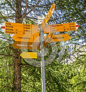 Yellow Signpost with directions to various hiking trails in Matterhorn, Zermatt, Switzerland, Europe