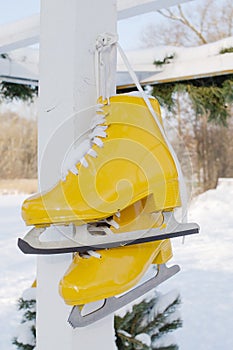 Yellow skates hang on the background of snowy nature. Sport and healthy lifestyle concept.