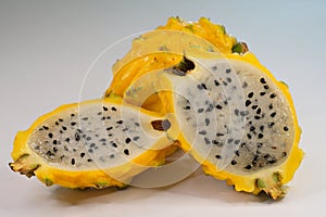 A yellow-skinned dragon fruit, or yellow pitaya, with white flesh, cut in half length-wise