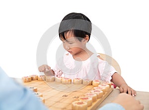 The yellow-skinned little girl is playing Chinese chess with an adult seriously