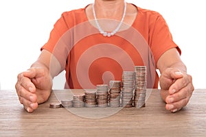 Yellow-skinned middle-aged woman pampers a row of increasing dollar coins with both hands