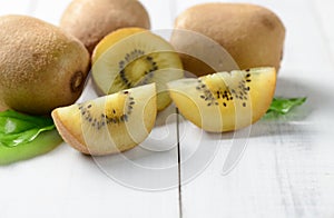 Yellow sliced kiwi fruit on white wood background.