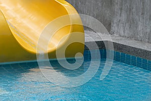 Yellow slider with blue swimming pool in summer time recreation background