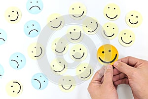 A yellow smiling face icon among a group of sad and happy face emoticons. Positivity, attraction and happiness. photo
