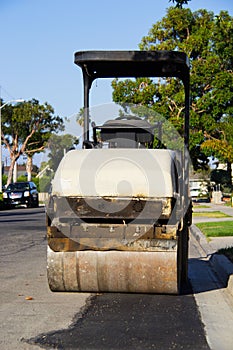 Yellow smooth drum roller parked in a residential neighborhood. photo