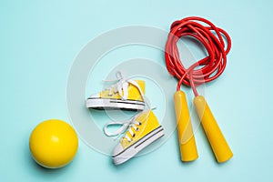 yellow sneakers, a red jump rope and a yellow ball lie on a blue background. sports and health