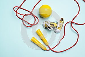 yellow sneakers, a red jump rope and a yellow ball lie on a blue background. sports for health