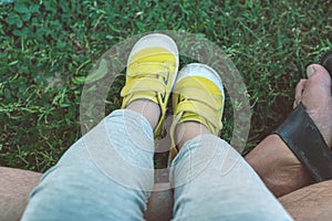 Yellow sneakers shoes sitting on father`s legs