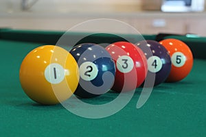 Yellow snooker ball with number one on it with other colorful balls placed in a row on a table