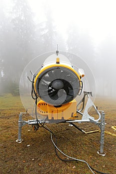 Yellow snow cannon from behind by foggy forest