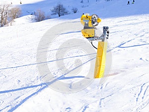 Yellow snow cannon on the ski slopes. Artificial snow making machine