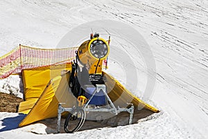 yellow snow generator on a snow slope at a resort on a sunny day.