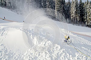 Yellow snow maker machine snow gun, snow cannon at ski slopes resort - standard equipment device for making snow to create bette