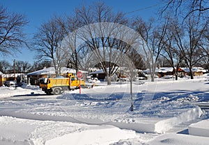 Yellow snow plow truck clearing snow in residential area. photo