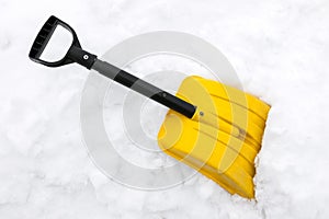 Yellow snow shovel on snow