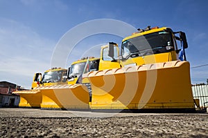 Yellow snowplow trucks in line photo