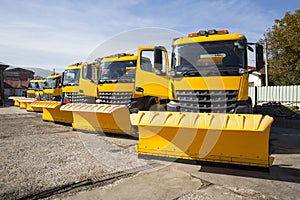 Yellow snowplow trucks in line photo