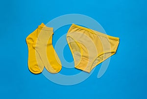 Yellow socks and yellow panties on a blue background. Flat lay