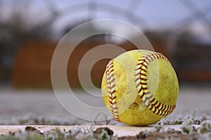 A yellow softball rests on the pitcher`s mound.