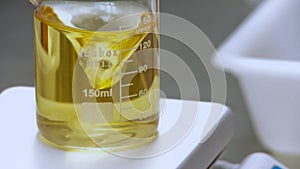 Yellow solution in a beaker agitated with magnetic stirred in the laboratory