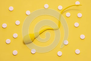 The yellow sperm model is on a yellow polka-dotted background made with white pills. Concept of diagnosis and treatment of male in photo