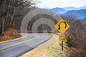 Yellow Spiral Curve Sign Along a Mountain Roadway