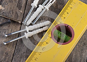 Yellow spirit level and bolts on the wooden table