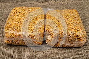 Yellow split peas in a cellophane bag on a background of coarse-textured burlap. Traditional grains for making soups and porridges