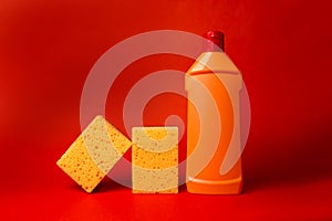 yellow sponge and orange bottle with cleaning on a red background. photo