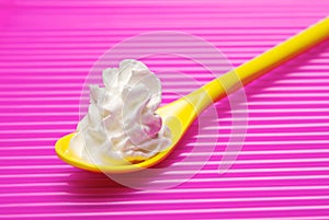 Yellow spoon and portion of whipped cream