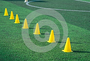 Yellow sport cones marker on soccer green grass pitch for children football training session