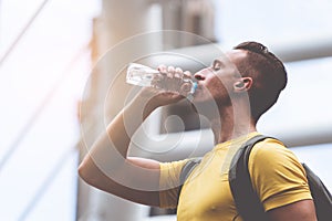 Yellow sporty guy drinking water in hot day outdoor