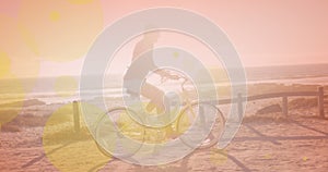 Yellow spots of light against caucasian woman riding a bicycle at the beach