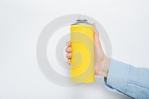 Yellow spray can for spraying in a female hand. No inscriptions. White background