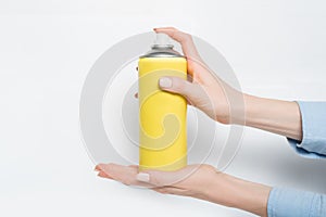 Yellow spray can for spraying in a female hands. No inscriptions. White background