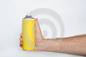 Yellow spray can for spraying in a male hand. No inscriptions. White background