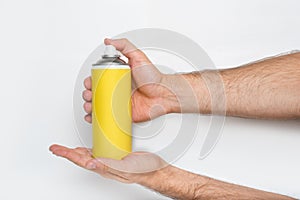 Yellow spray can for spraying in a male hands. No inscriptions. White background