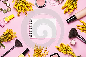 Yellow spring flowers, notebok and some cosmetics on pink spring background photo