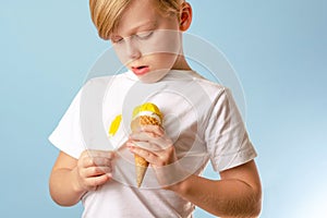 A yellow stain on the clothes. Ruining clothes. A child showing the stain of ice cream on a white T-shirt