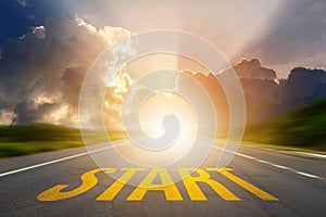 Yellow START word on asphalt highway road with sunset or sunrise light above asphalt road. Start Your Life. Conceptual image